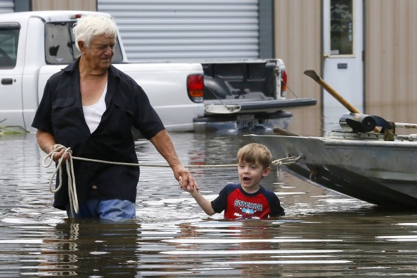 man and child wading through flood water near home