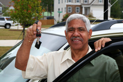 man holding up keys and standing with car door open