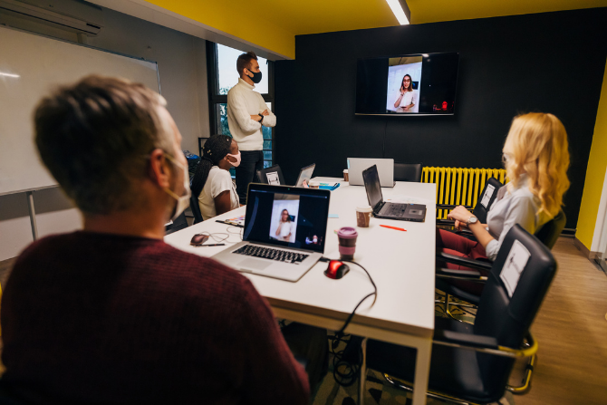 A video conferencing meeting taking place with people wearing face masks