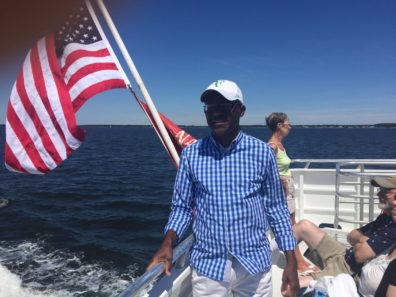 smiling man in front of flag on boat