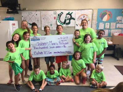 group of children with giant donation check