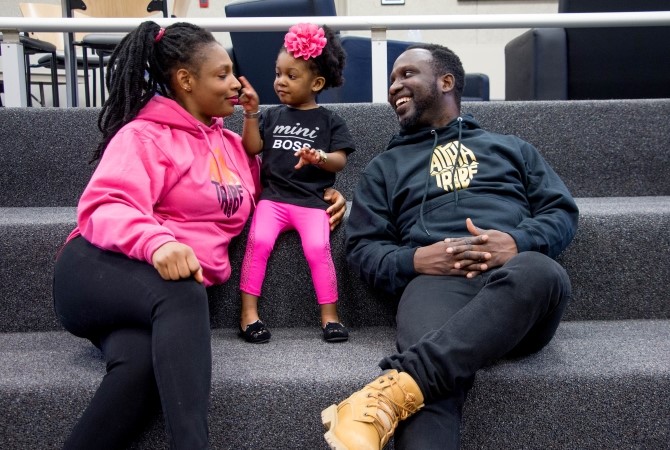 A young Black family lounge on some stairs