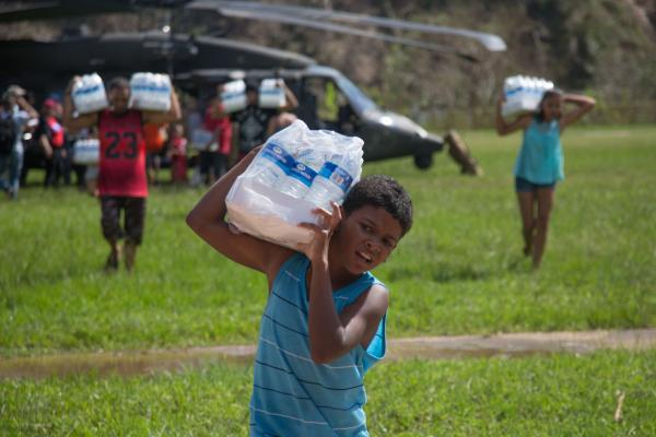 child hauling bottled water away from helicopter