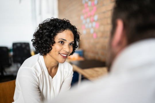 A woman and man talking in an office.