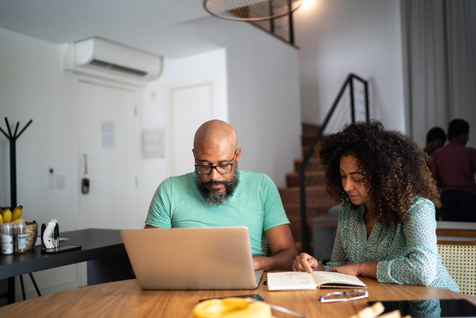 A man and woman at a table looking at a laptop