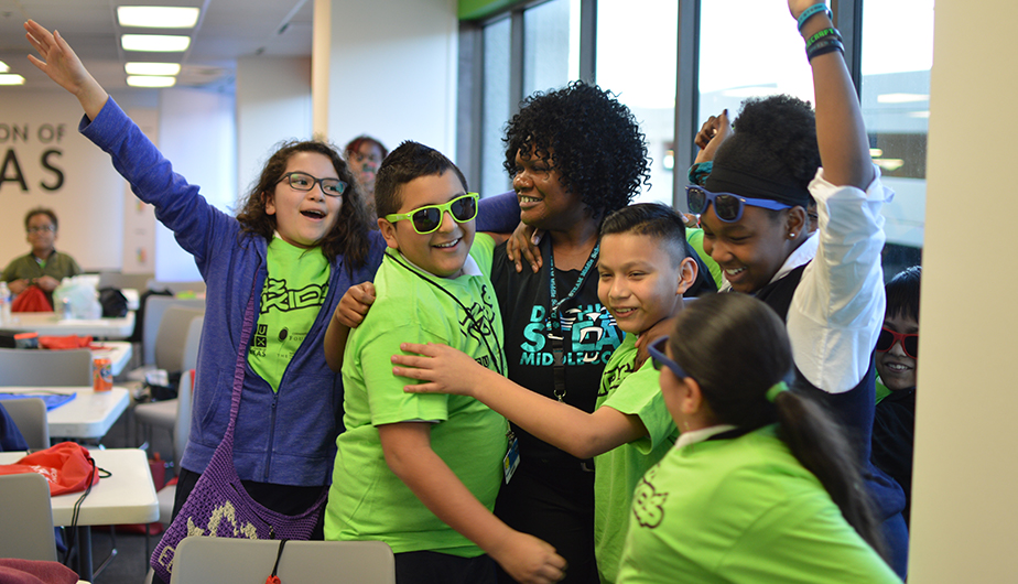 smiling and hugging group of enthused kids and teacher