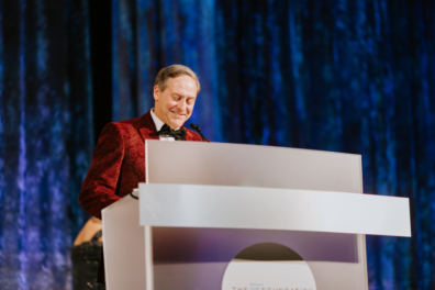 well dressed man speaking at podium for awards