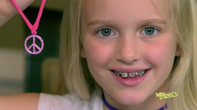 close up of blonde child with braces smiling