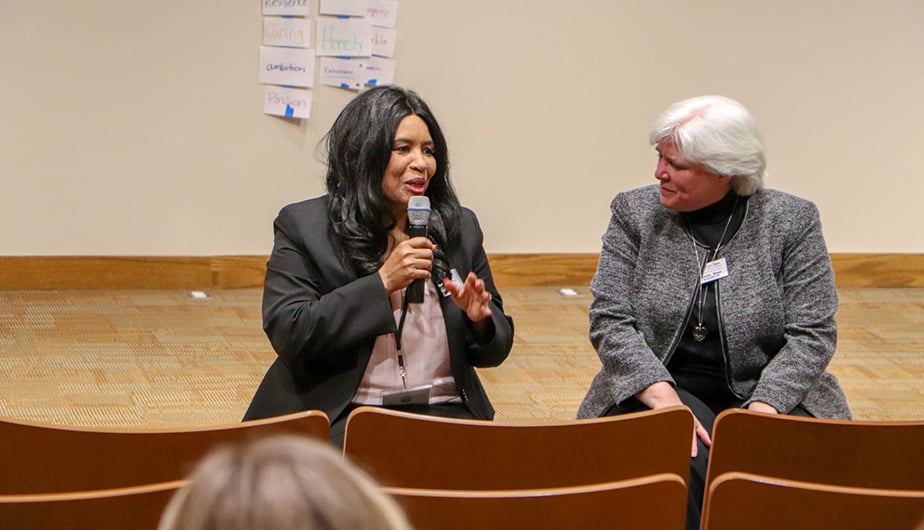 woman with microphone speaking to second guest on stage